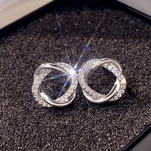 Detailed close-up of silver interlocking hoop earrings with white cubic zirconia in a box
