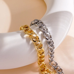 Polished gold and silver stainless steel chunky Cuban link chains on a white stand