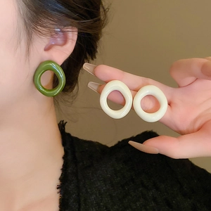 Detailed view of olive green and cream resin geometric hoop earrings on ear