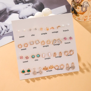 Set mit 16 Paar goldenen Minimalismus-Ohrsteckern mit Perlen und Zirkon auf Displaykarte