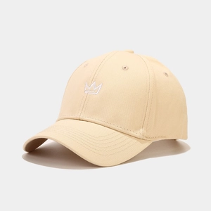 Close-up of white crown embroidery and cotton fabric texture on a beige baseball cap