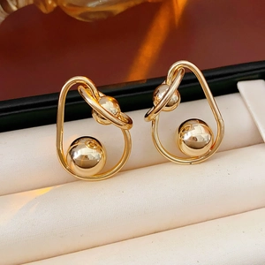 Detail of golden geometric hoop earrings with a sphere pendant in a white jewelry box