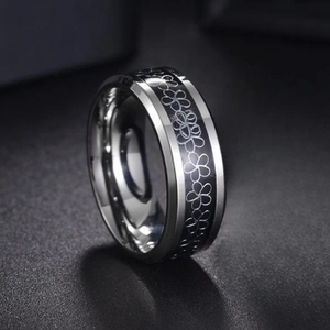 Macro detail of 8mm titanium steel ring with black enamel floral patterns and polished beveled edges