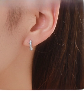 Close-up of S925 silver hoop earrings with blue zircon and pavé crystals on ear