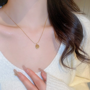 Gros plan d'un collier en acier inoxydable doré avec pendentif ovale sur un modèle