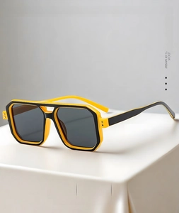 Close-up of yellow and black two-tone frame aviator sunglasses on white pedestal