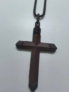 Vue macro d'un pendentif croix en bois brun avec pointes en métal noir et sa chaîne