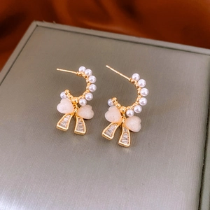 Detail of gold bow earrings with white pearls and sparkling cubic zirconia stones