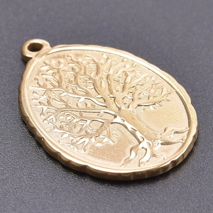 Macro shot of a golden oval Tree of Life pendant with detailed embossed metal texture