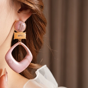 Pink and orange resin geometric earrings shown on model with retro marbled textures
