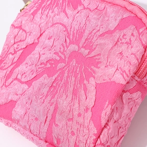 Detailed close-up of pink jacquard fabric floral pattern and golden zipper on canvas pouch