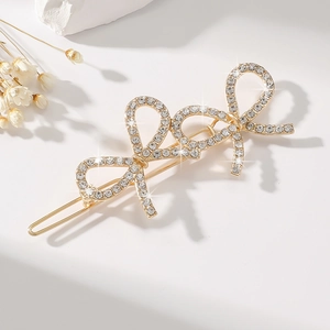 Close-up of gold hair clip with three rhinestone-encrusted bows and elegant metallic finish
