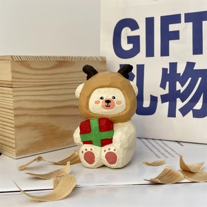 Macro shot of hand-carved wooden bear figurine holding a red gift box on wood shavings