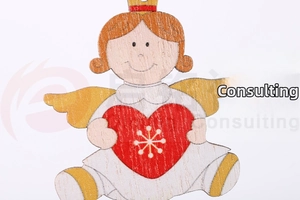 Macro shot of a wooden Christmas angel ornament with red heart and gold wings