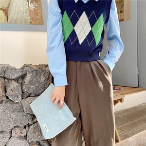 Detail of light blue corduroy cosmetic bag held by a model in a retro casual outfit