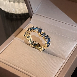 Detailed macro view of a gold-plated ring featuring a deep blue stone in a jewelry box
