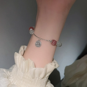 Detail eines gedrehten Silberarmbands mit Opalperlen und rundem Anhänger am Handgelenk