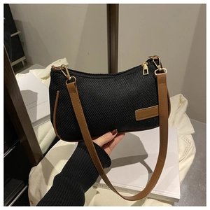 Close-up of black woven shoulder bag with brown leather trim and golden metal zipper details
