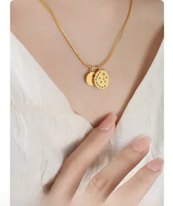 Close-up of golden snake chain necklace with zircon round pendant and engraved good disc