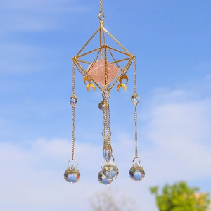 Golden geometric suncatcher with rose quartz and crystal spheres against clear blue sky