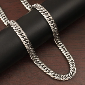 Detailed close-up of a silver Cuban link chain necklace wrapped on a dark cylinder