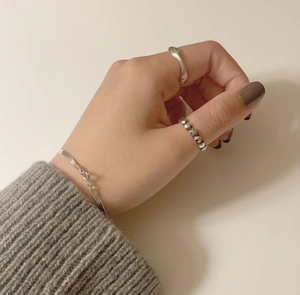 Minimalist 925 sterling silver rings and snake chain bracelet shown on a soft knit sweater