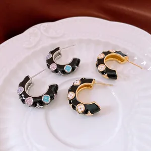 French vintage C-shaped hoop earrings with colorful enamel flowers on black background