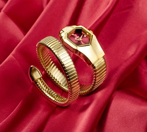 Detailed macro view of a gold snake-shaped luxury watch with a vibrant red dial on silk