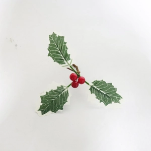 Detailaufnahme von künstlichen grünen Blättern mit roten Beeren für Weihnachtsservietten