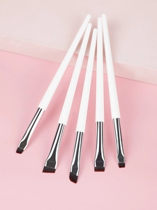 Five angled eyeliner brushes with white handles and silver ferrules on pink background