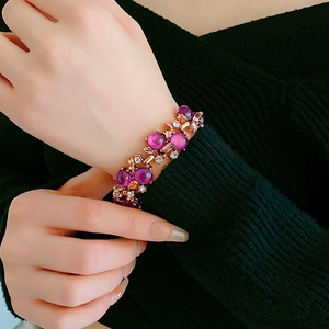 Detail of vintage gold flower bracelet with purple cat-eye beads and rhinestones