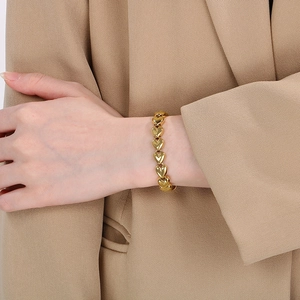 Detailed view of the gold-toned bracelet with interconnected 3D heart links on the wrist