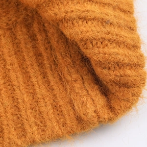 Gros plan du pull à capuche en mohair orange avec texture moelleuse et détails de tricotage