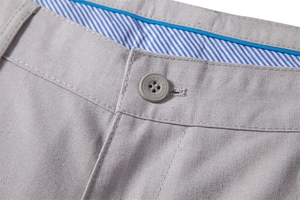 Detailed macro view of men's linen pants waistband with fashion button and striped lining