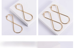 Macro shot of large infinity-shaped golden titanium steel earrings on stone block