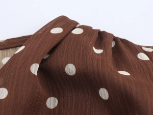 Détail macro du tissu en mousseline marron à pois blancs montrant texture et drapé