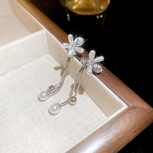 Macro detail of silver needle flower earrings with pearls and long tassel fringe
