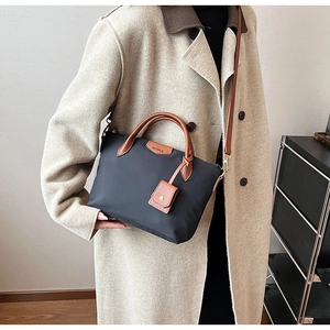 Detail of navy nylon tote bag with brown leather handles and adjustable shoulder strap