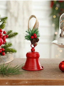 Detail of red metal Christmas bell with pine needles, red berries and jute rope
