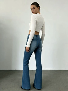 Vue arrière du jean évasé bleu ajusté associé à un haut court en maille blanc chic