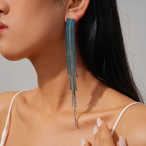 Close-up of model wearing long tassel earrings with blue, green, and silver rhinestones