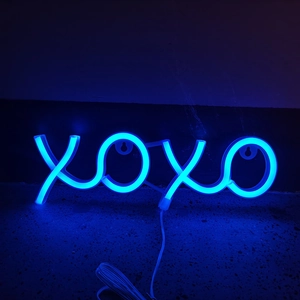 Blue XOXO LED neon sign glowing on dark wall background with visible power cord