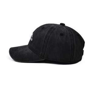 Detailed side view of a black washed denim baseball cap with mountain peak embroidery