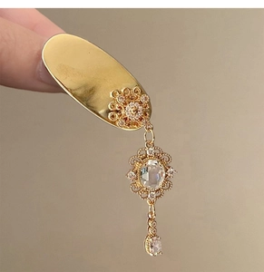 Close-up of vintage golden fringe hair clip with transparent gemstones and tassel details