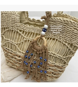 Detail of woven straw tote bag with evil eye charm tassels and neutral interior lining