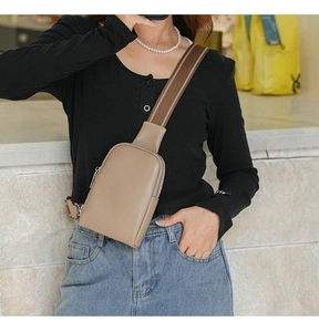 Close-up of beige crossbody chest bag with striped woven strap shown on a model