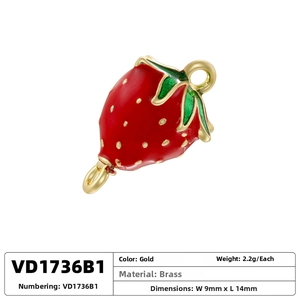 Macro shot of red enamel strawberry pendant with gold plating and green leaf detail