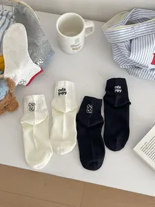 Detail of embroidered cartoon puppy and cute pupy text on cotton crew socks