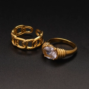 Detail of gold chain link ring and chunky ring with oval clear zircon on black surface