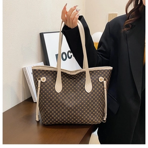 Detailed close-up of brown geometric print tote bag with white faux leather handles